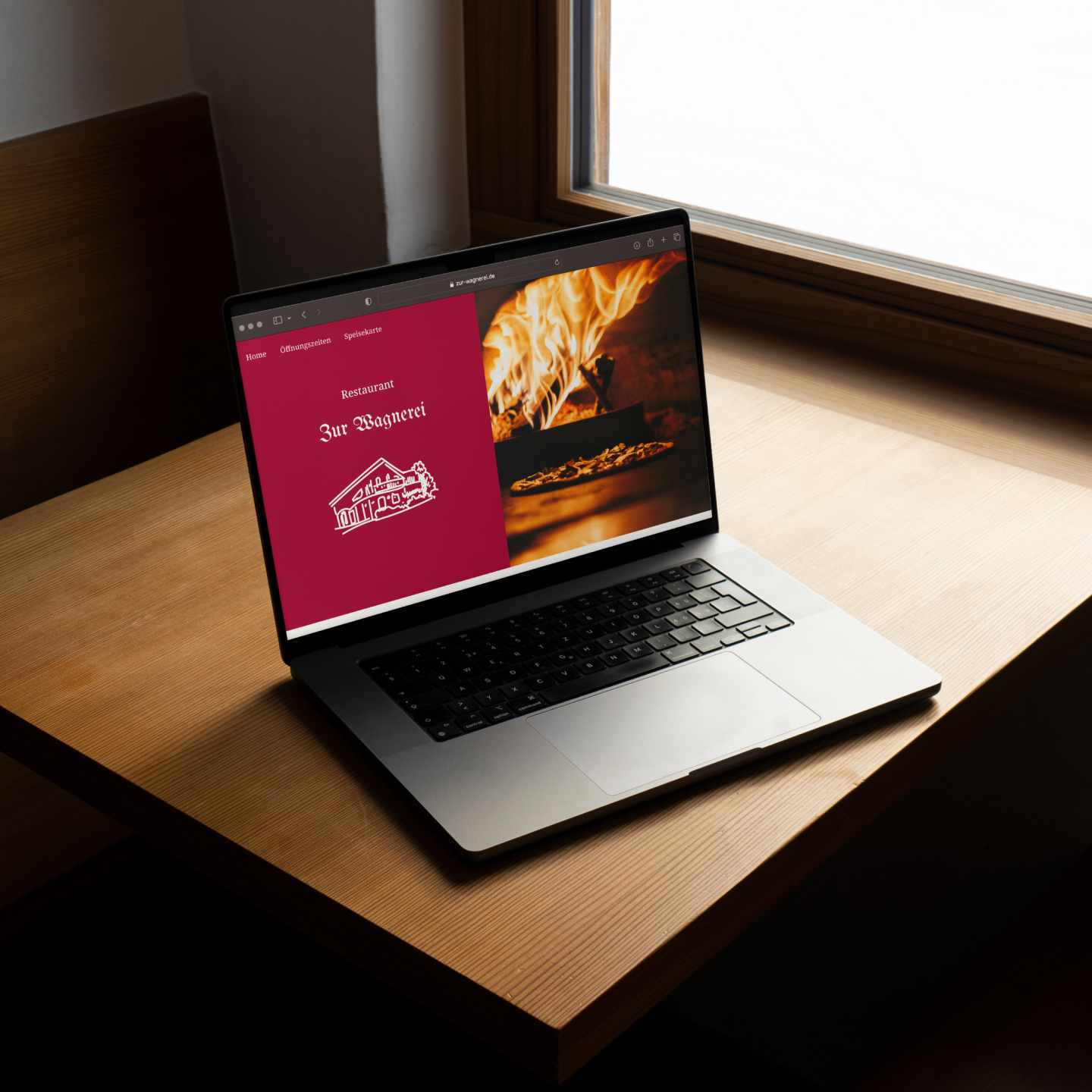Startseite der Zur Wagnerei Website in einem Macbook, das auf einem Holztisch steht.